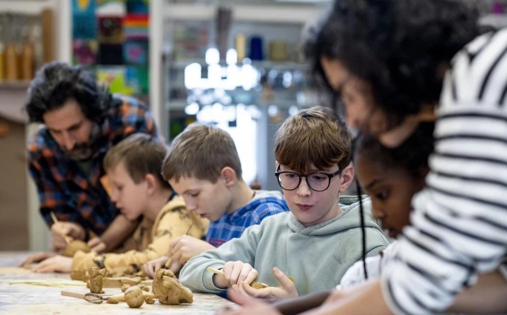 Kneden op muziek, met je ogen dicht. Groep 8 van De Twiner uit Sint Jacobiparochie leert kleien én Engels van Koerdische vluchtelingen